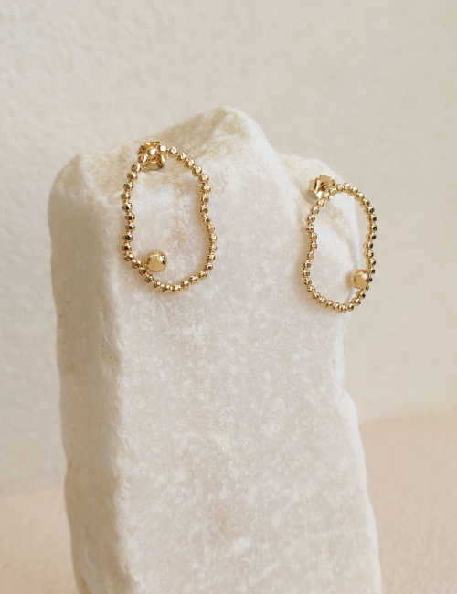 Découvrez les boucles d'oreilles Sane, alliant minimalisme et élégance. Conçues en métal doré avec un design unique et léger, el